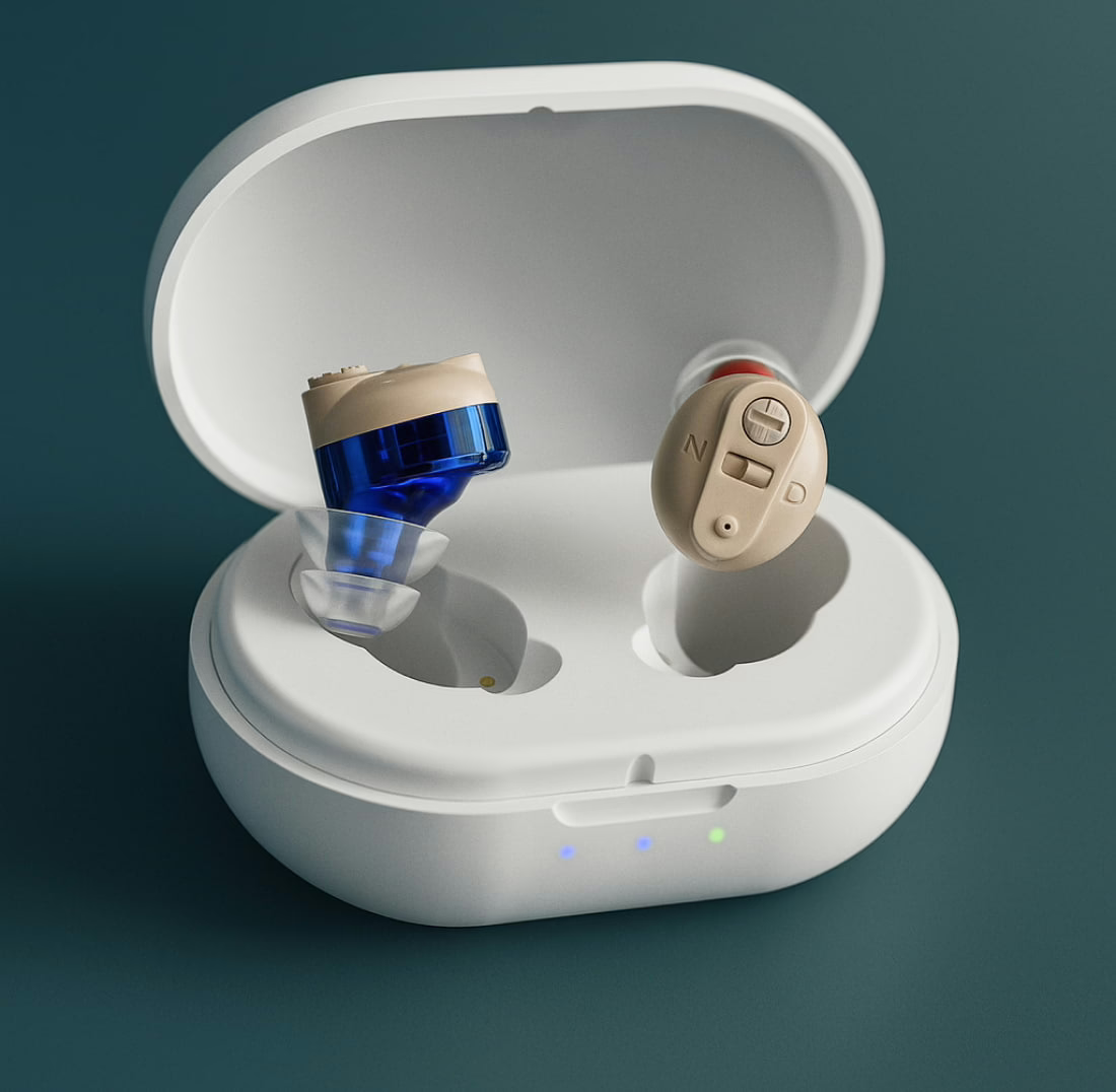 OmniHear in-ear hearing devices — one beige with volume dial, one with blue translucent shell — resting in an open white charging case
